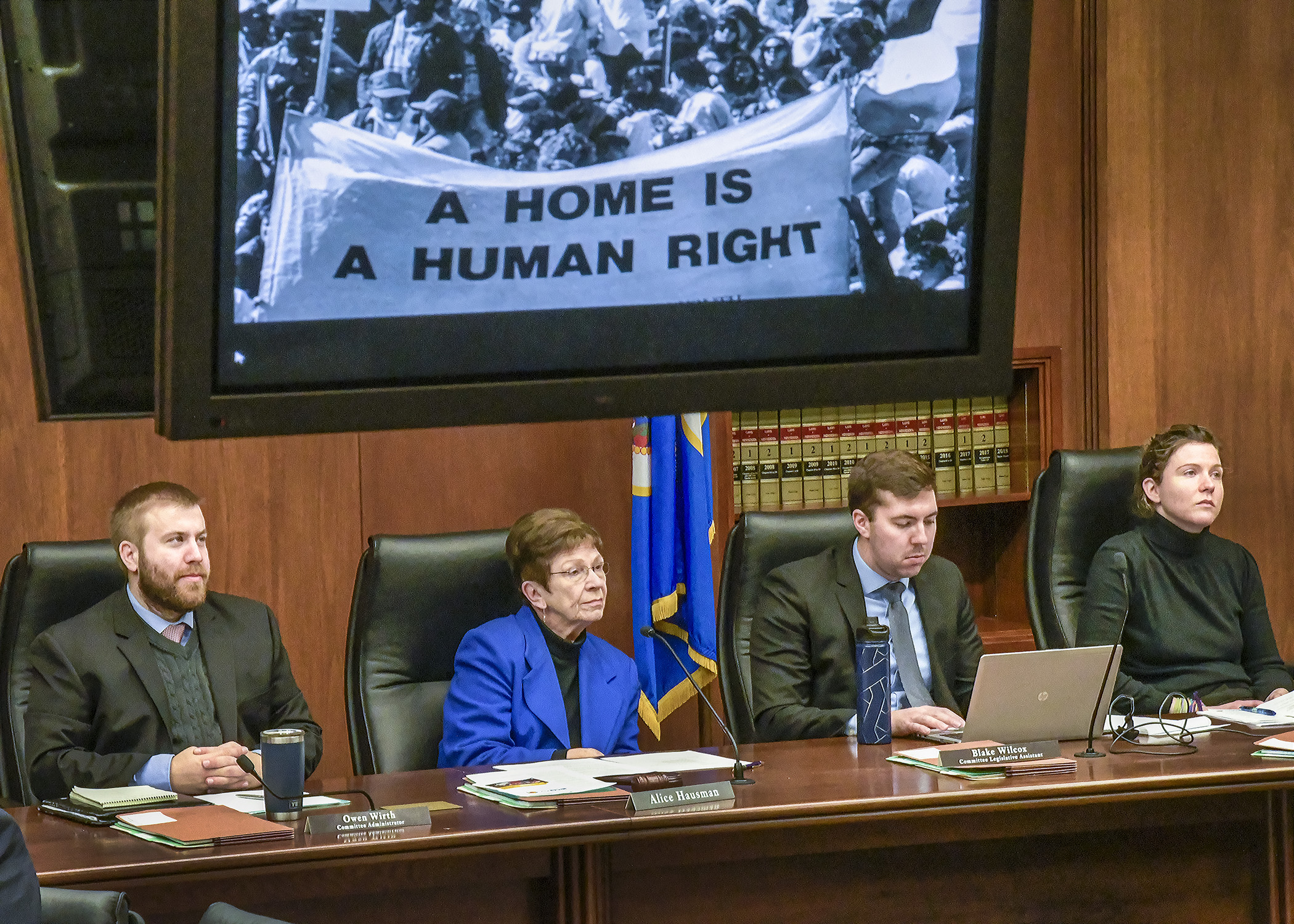 Members of the House Housing Finance and Policy Division view a video about the housing crisis to open a Jan. 22 hearing on housing issues facing refugee communities. Photo by Andrew VonBank